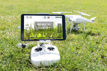 Digital tablet attached to drone controller showing ready to takeoff command on grassy field