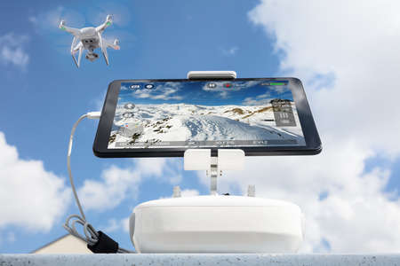 Low angle view of drone filming mountains seen on tablet computer against cloudy sky