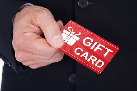 Close-up Of Man's Hand Holding Gift Cardの写真素材