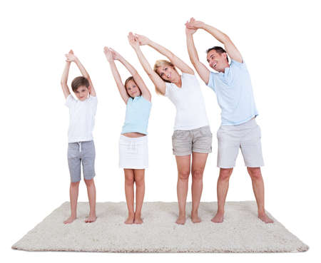 Smiling Couple With Their Two Children Exercising Against White Backgroundの写真素材