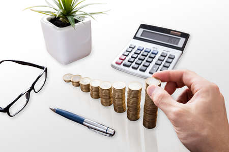 Close-up Of A Businessperson's Hand Stacking Coins In Officeの写真素材