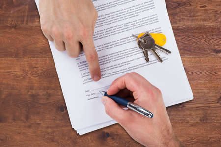 High Angle View Of A Real Estate Agent's Hand Helping Client In Filling Contract Formの写真素材
