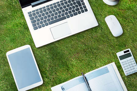 Elevated View Of Electronic Devices With Diary On Green Grassの写真素材