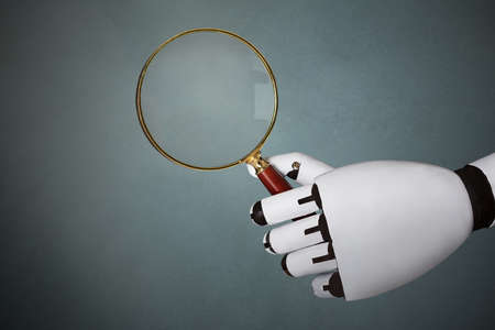 Close-up Of Robot's Hand Holding Magnifying Glass