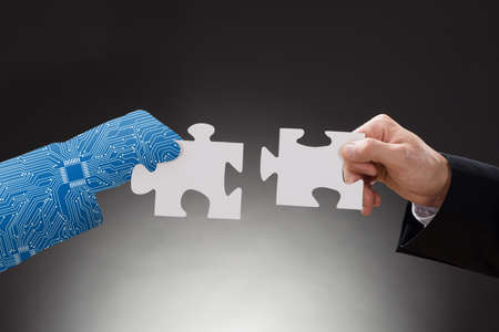 Digital Generated Human Hand And Business Man Holding A Piece Of Jigsaw Puzzle