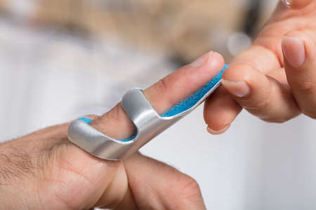 Close-up Of A Physician Holding Person's Finger With Brace In Clinic