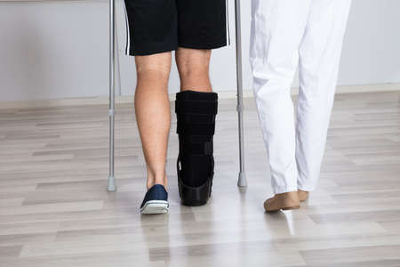 Low Section View Of Physiotherapist And Injured Person's Leg Wearing Walking Braceの写真素材