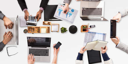 Businesspeople Using Electronic Device While Working On Graph In Office