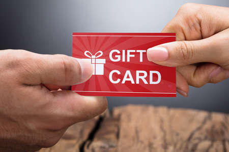 Close-up Photo Of Hands Exchanging Gift Cardの写真素材