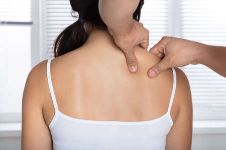 Rear View Of A Young Woman Receiving Shoulder Massage From Masseurの写真素材