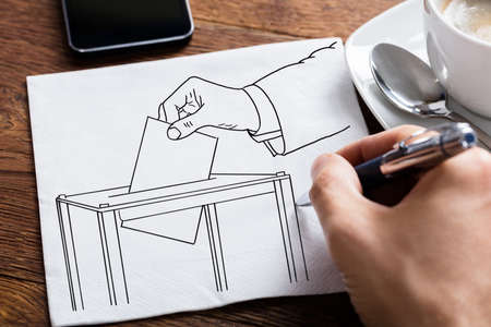 Close-up Of Person's Hand Drawing Ballot Box On Paperの写真素材