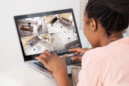 Close-up Of African Woman Looking At Laptop Monitoring Video Footage At Home
