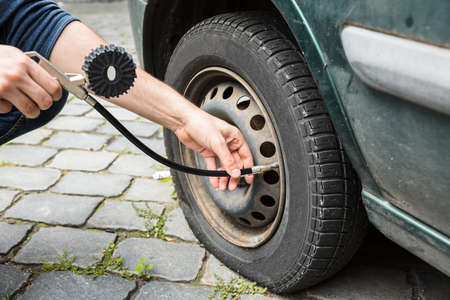 Person's Hand Measuring Car Tyre Pressure With Pressure Gauge Outdoorsの写真素材