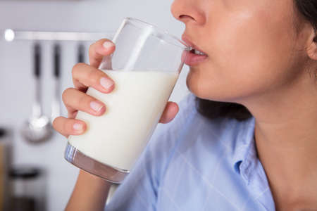 Close-up Of A Woman Drinking Glass Of Fresh Milk At Homeの写真素材