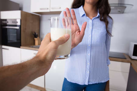 Woman Rejecting Glass Of Milk Offered By Personの写真素材