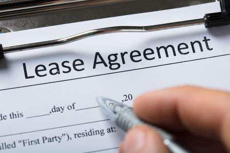 Close-up Of A Human Hand Filling Lease Agreement Form With Penの写真素材