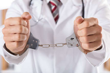 Close-up Of Arrested Doctor's Hand With Handcuffsの写真素材