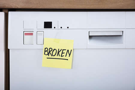 Close-up Of A Dishwasher With Adhesive Notes Showing Broken Textの写真素材