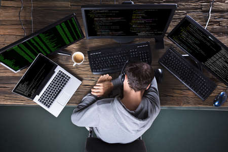 Elevated View Of Sleeping Man With Multiple Computer And Laptop On Deskの写真素材