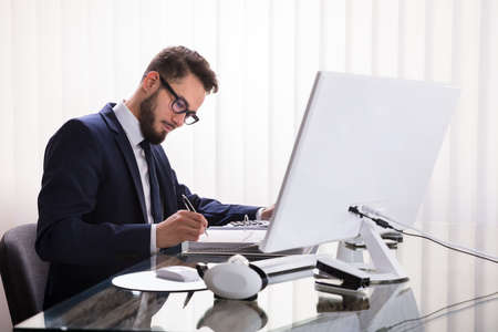 Businessman Calculating Bill With Calculator In Officeの写真素材