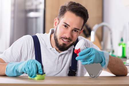Portrait Of A Happy Young Man Cleaning Kitchen Worktopの写真素材