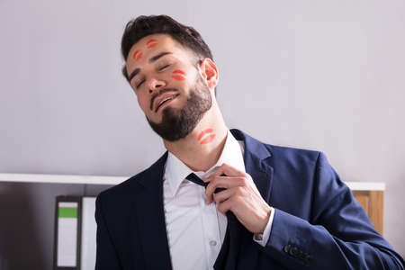 Close-up Of A Young Businessman With Lipstick Kiss Marks On Face