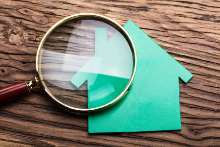 Closeup Of Magnifying Glass And Green Paper House On Woodの写真素材