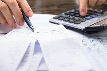 Close-up Of A Businessperson Calculating Receipt With Calculatorの写真素材