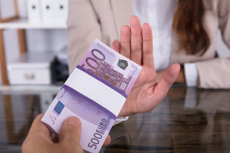 Close-up Of Businesswoman Hand Refusing To Take Bribe From Partner At Workplace