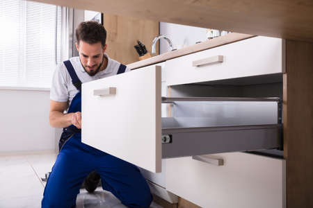 Young Handyman In Overall Installing Drawer In Kitchenの写真素材