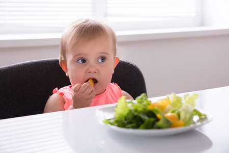 Close-up Of A Baby Girl Eating Healthy Food At Breakfastの写真素材