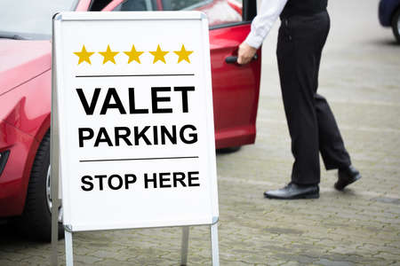 Close-up Of Male Valet Standing Near Valet Parking Signの写真素材