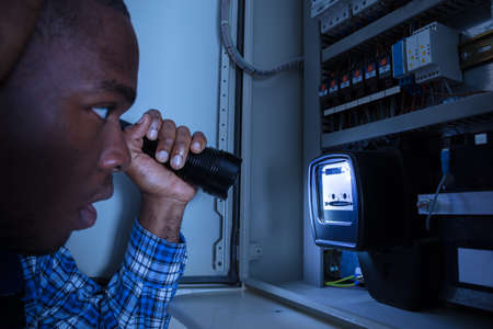 Close-up Of A Electrician Examining A Electric Meter With A Torchの写真素材