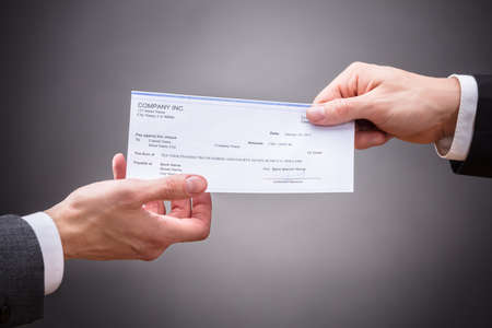 Businessperson Giving Cheque To Colleague On Grey Backgroundの写真素材