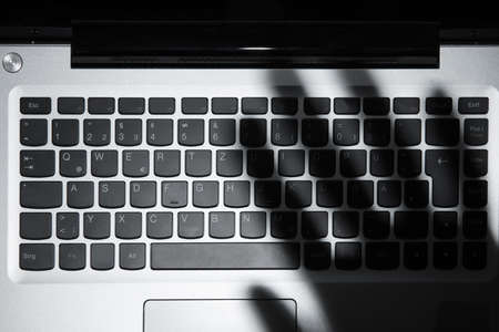 High Angle View Of Human Hand's Shadow Falling On Laptop Keypadの写真素材