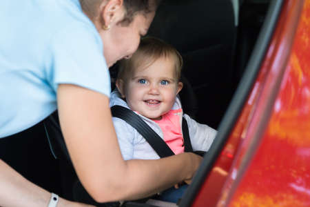 Close-up Of A Mother Taking Care Of Her Cute Little Baby Girl In Carの写真素材