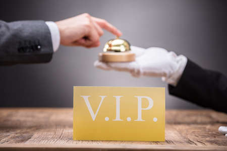 Close-up Of Vip Card In Front Of Person Ringing Service Bell Held By Waiterの写真素材