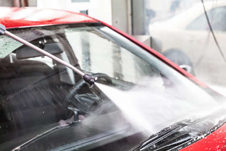 High Pressure Water Jet Washing Red Car At Service Station