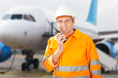 Portrait Of A Happy Male Ground Crew Talking On Walkie-talkieの写真素材