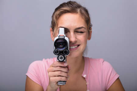 Close-up Of A Smiling Young Woman Looking Through Lens Of Retro Camera