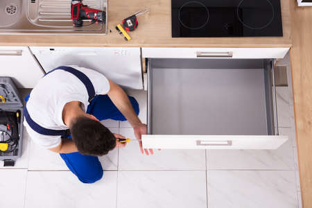High Angle View Of Male Carpenter Fixing Drawer In Kitchenの写真素材