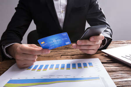 Close-up Of A Businessperson's Hand Shopping Online With Mobile Phone And Credit Cardの写真素材