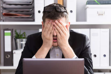 Close-up Of A Tired Young Businessman Sitting In Office