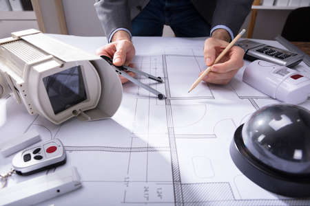 Close-up Of An Architect's Hand Drawing Plan On Blueprint With Pencilの写真素材