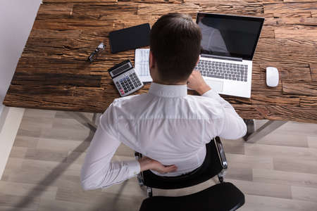 High Angle View Of A Businessman Suffering From Back Pain In Office