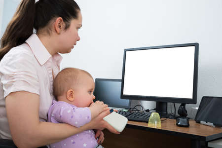 Woman With Her Baby Using Computer With Blank White Screenの写真素材