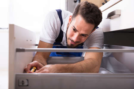 Close-up Of A Young Male Carpenter Installing Drawer With Screwdriverの写真素材
