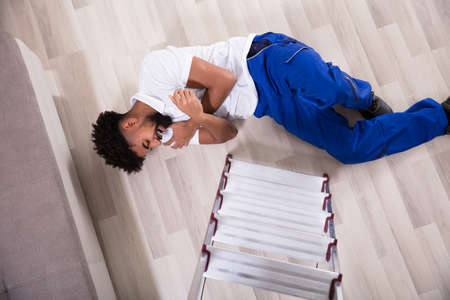 Young Handyman Falling From The Ladder In The Living Room Got Hurt On His Arms