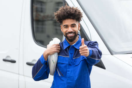 Portrait Of Smiling Electrician With White Cable Coil Standing By Vanの写真素材