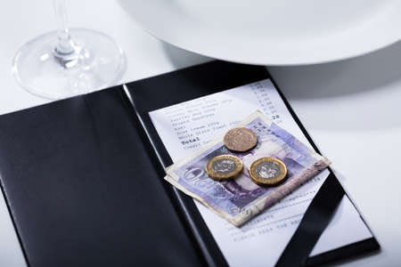 Elevated View Of Pound Banknotes And Bill In Folder Payment On Table